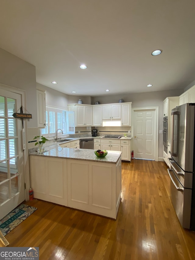 kitchen featuring sink, kitchen peninsula, light hardwood / wood-style flooring, white cabinetry, and stainless steel appliances