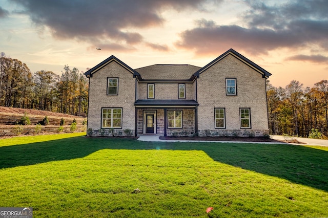 view of front of house featuring brick siding and a yard