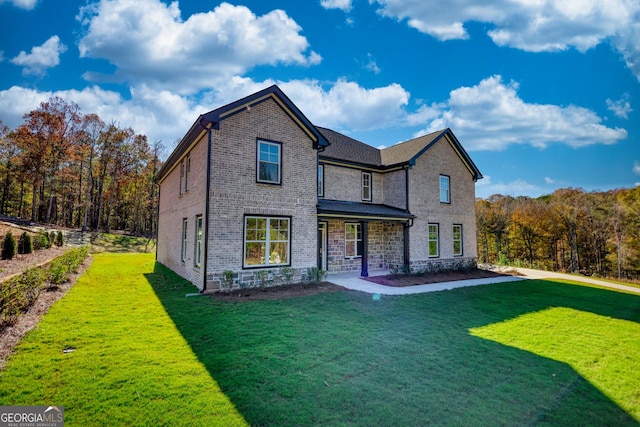 view of front of property featuring covered porch, brick siding, and a front yard