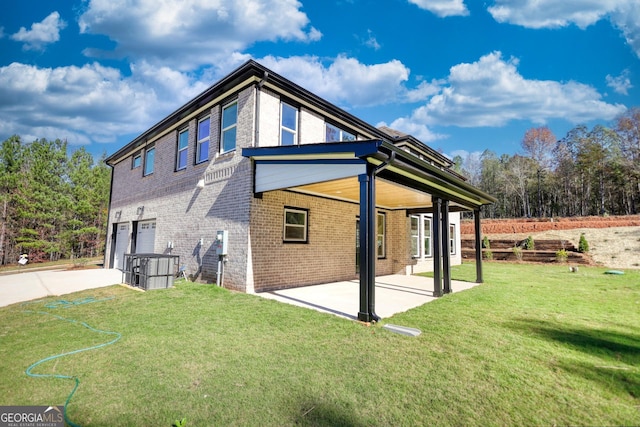 back of property with a garage, brick siding, a yard, concrete driveway, and a patio area