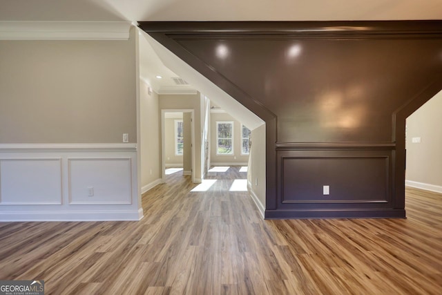 bonus room featuring light wood-type flooring, visible vents, a decorative wall, and baseboards