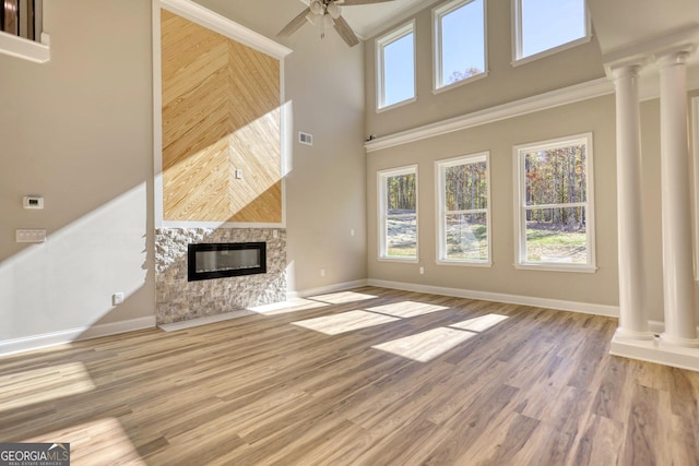 unfurnished living room with a multi sided fireplace, light wood finished floors, and ornate columns