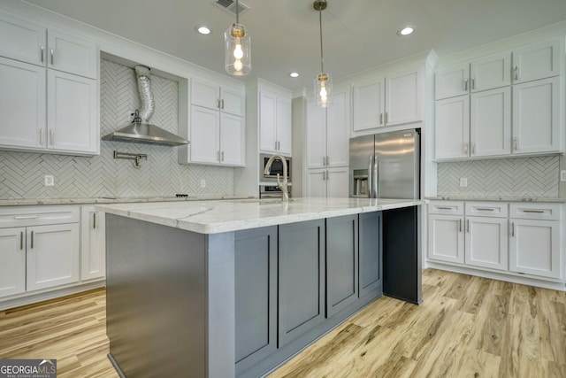 kitchen with a kitchen island with sink, stainless steel appliances, light wood-style flooring, and white cabinetry