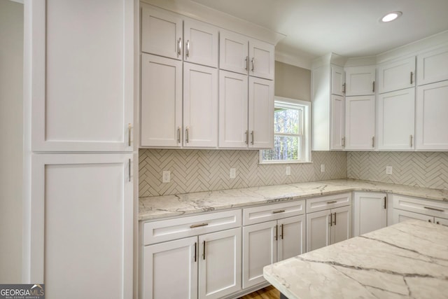 kitchen with tasteful backsplash, recessed lighting, white cabinets, and light stone countertops