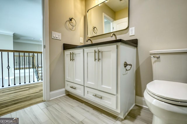 bathroom featuring toilet, wood finished floors, vanity, and baseboards