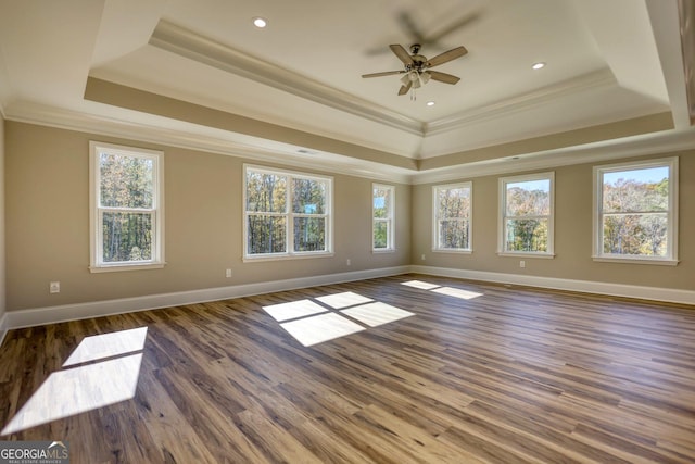 empty room with dark wood-style floors, baseboards, ornamental molding, and a raised ceiling