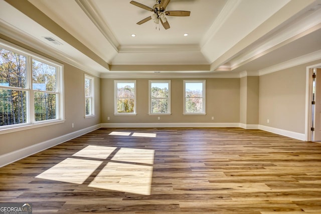 unfurnished room with light wood-style floors, a raised ceiling, visible vents, and crown molding