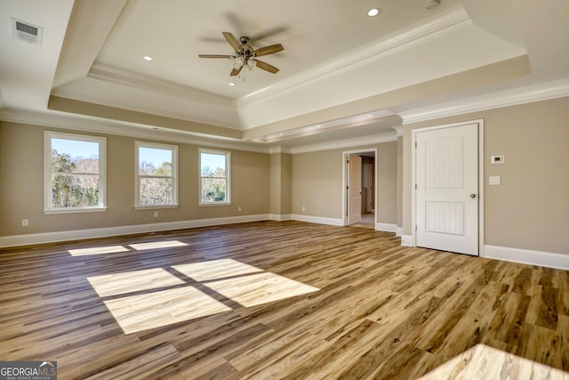 unfurnished living room with a wealth of natural light, a raised ceiling, visible vents, and crown molding