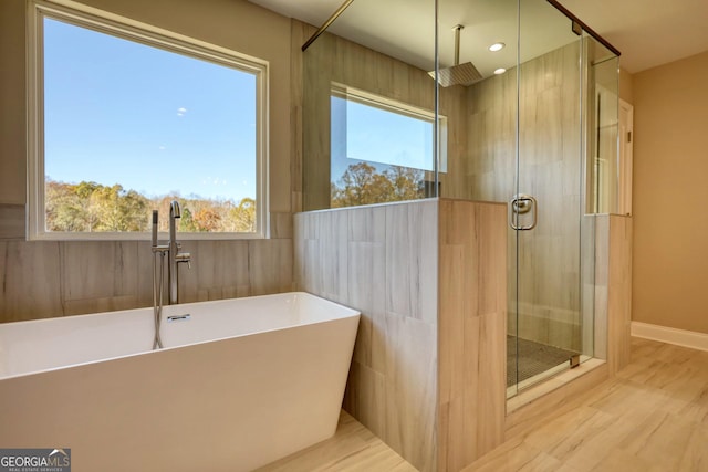 bathroom featuring a stall shower, a soaking tub, and baseboards