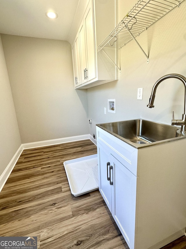 clothes washing area with hookup for a washing machine, cabinet space, a sink, and wood finished floors