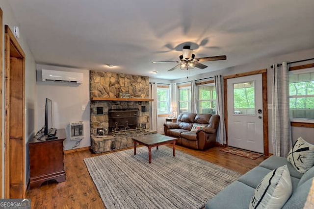 living room featuring ceiling fan, a stone fireplace, a wall mounted AC, heating unit, and hardwood / wood-style flooring