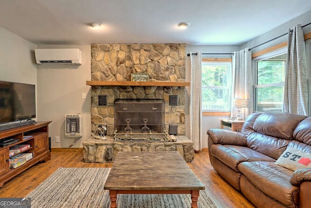 living room featuring a wall mounted AC, hardwood / wood-style floors, heating unit, and a fireplace