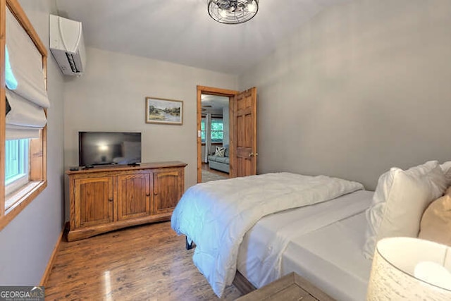 bedroom with light hardwood / wood-style floors and an AC wall unit