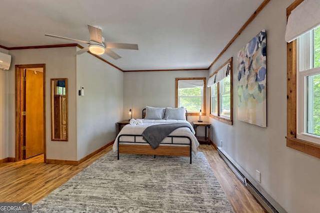 bedroom with multiple windows, ceiling fan, a baseboard radiator, and hardwood / wood-style flooring