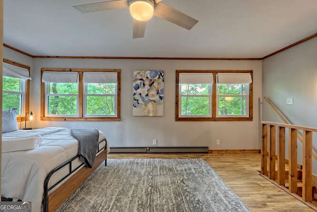 bedroom featuring ceiling fan, light hardwood / wood-style flooring, baseboard heating, and multiple windows