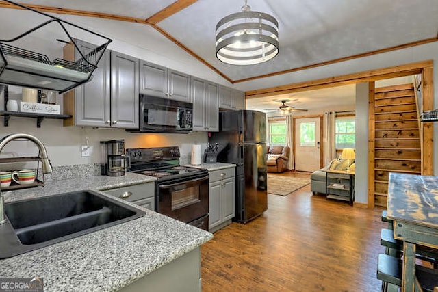 kitchen with hardwood / wood-style floors, lofted ceiling, black appliances, sink, and light stone counters