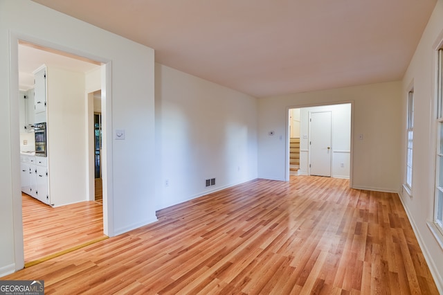 unfurnished bedroom with light wood-type flooring and connected bathroom