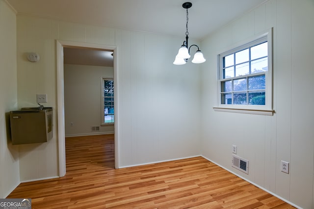 unfurnished dining area featuring a notable chandelier and light wood-type flooring