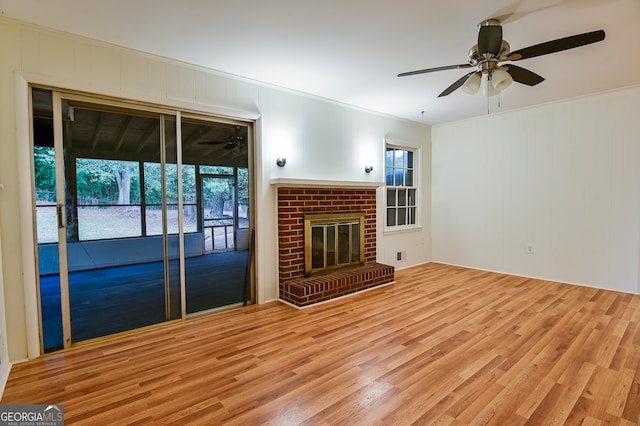 unfurnished living room with ceiling fan, light wood-type flooring, crown molding, and a brick fireplace