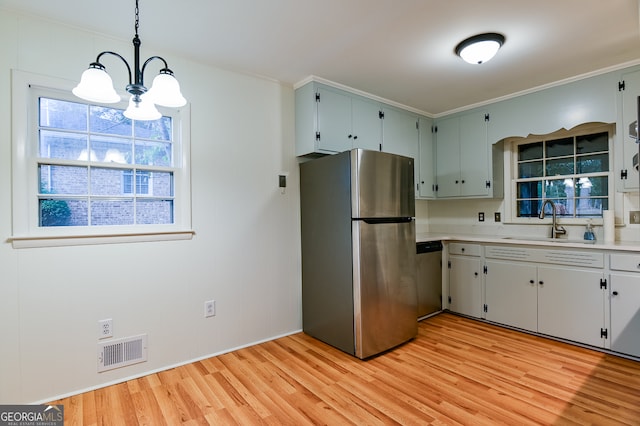 kitchen featuring sink, hanging light fixtures, stainless steel appliances, light hardwood / wood-style flooring, and a notable chandelier