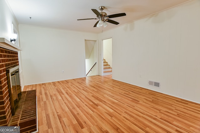 unfurnished living room with ceiling fan, ornamental molding, a fireplace, and light hardwood / wood-style flooring