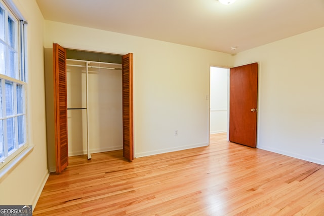 unfurnished bedroom with multiple windows, a closet, and light hardwood / wood-style flooring