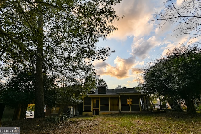 back house at dusk with a sunroom