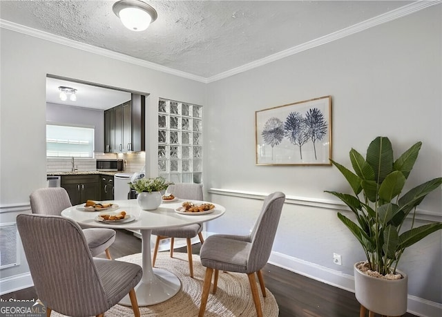 dining room with dark wood-style floors, crown molding, a textured ceiling, and baseboards