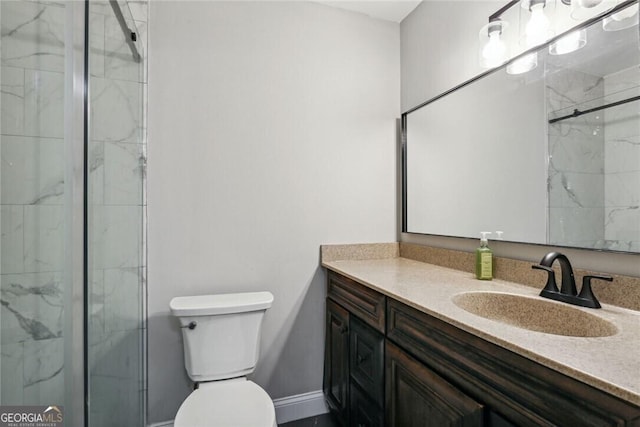 bathroom featuring a marble finish shower, vanity, toilet, and baseboards