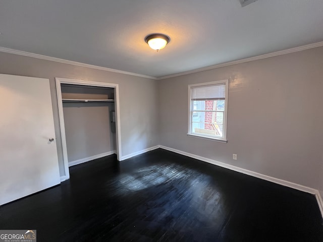 unfurnished bedroom featuring dark hardwood / wood-style flooring, crown molding, and a closet