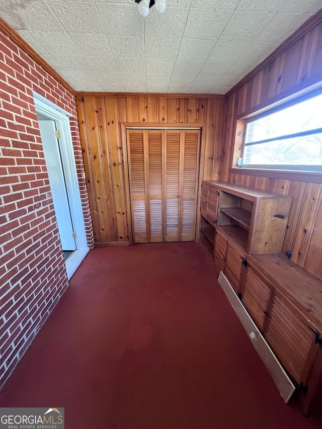 interior space with dark carpet, wooden walls, and brick wall