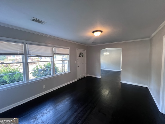 spare room featuring a chandelier, dark hardwood / wood-style flooring, and ornamental molding