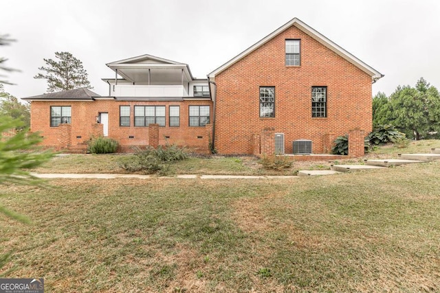 rear view of house featuring central AC and a lawn