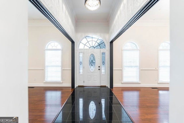 entrance foyer featuring dark hardwood / wood-style floors, ornamental molding, and a notable chandelier