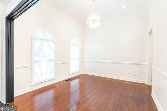 spare room featuring a chandelier, crown molding, and dark wood-type flooring