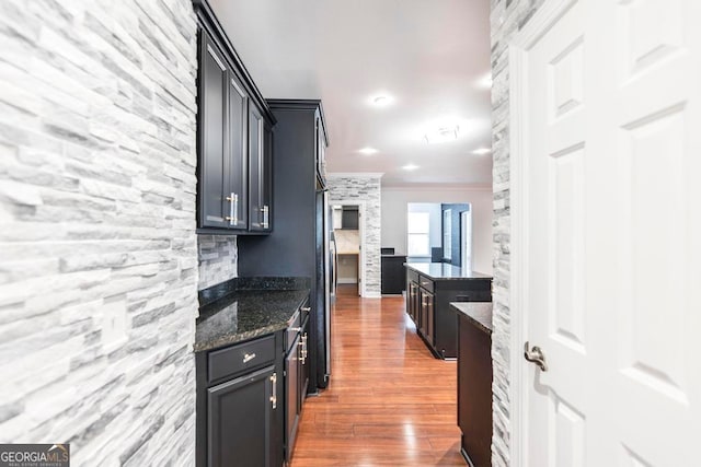 kitchen with dark stone countertops, dark wood-type flooring, and ornamental molding