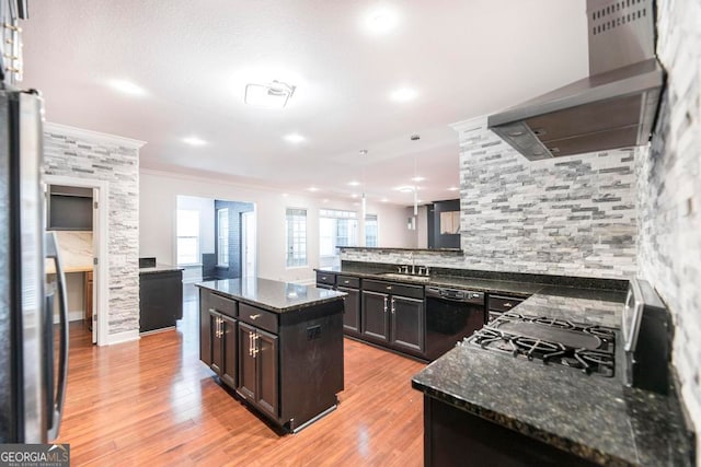 kitchen with dishwasher, wall chimney range hood, light wood-type flooring, decorative light fixtures, and a kitchen island