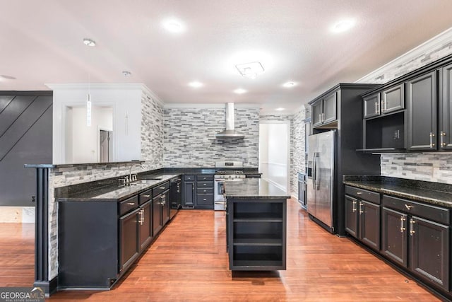 kitchen featuring backsplash, wall chimney exhaust hood, light wood-type flooring, and stainless steel appliances