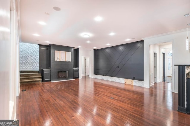 unfurnished living room with ornamental molding, a large fireplace, and dark wood-type flooring