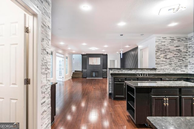 kitchen featuring decorative light fixtures, a center island, dark hardwood / wood-style flooring, and dark stone counters