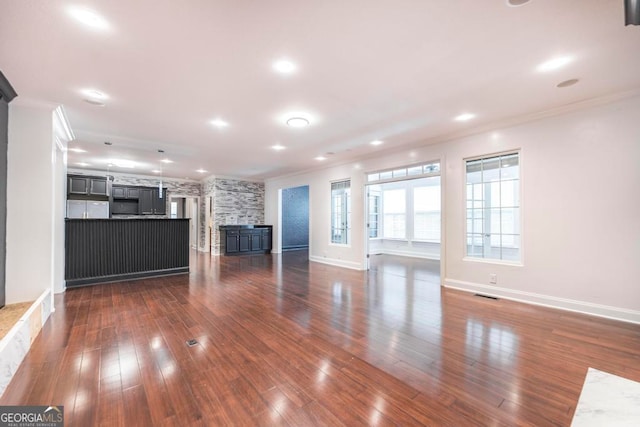 unfurnished living room featuring ornamental molding and dark wood-type flooring