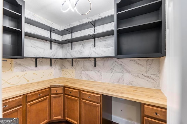 kitchen with butcher block counters, decorative backsplash, and built in desk