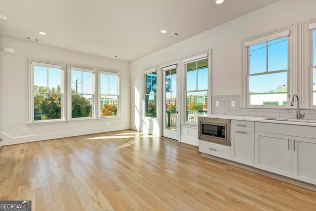 kitchen with white cabinets, a healthy amount of sunlight, stainless steel microwave, and sink