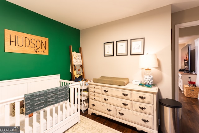 bedroom featuring dark hardwood / wood-style floors and a nursery area