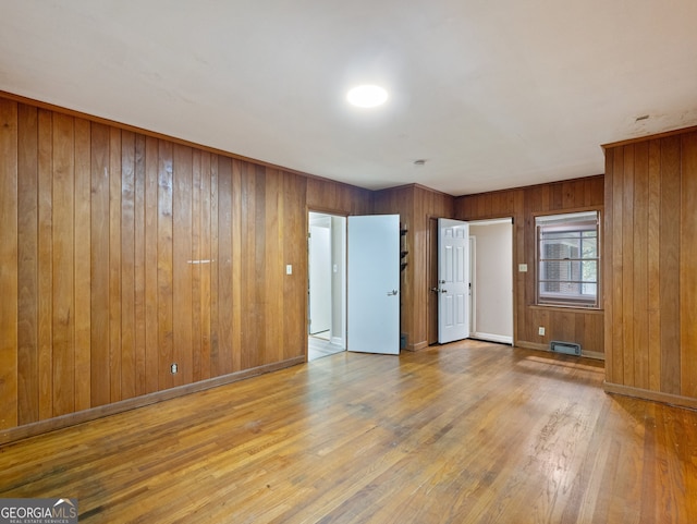 empty room with wooden walls and light wood-type flooring