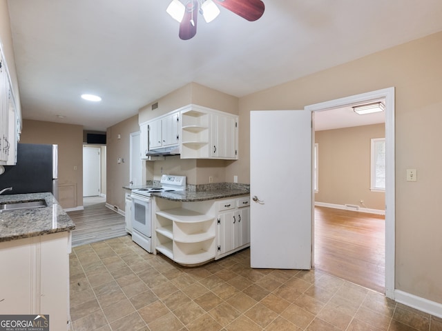 kitchen with stainless steel fridge, sink, electric stove, dark stone countertops, and white cabinetry