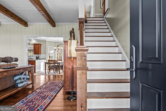 stairs with beamed ceiling, a chandelier, and hardwood / wood-style floors