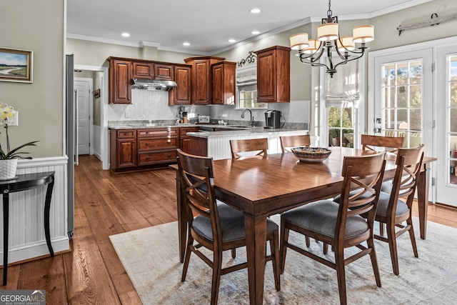 dining area featuring ornamental molding, dark wood-type flooring, sink, and a chandelier