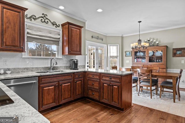 kitchen with stainless steel dishwasher, ornamental molding, sink, and hanging light fixtures