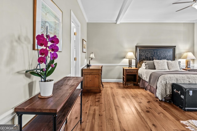 bedroom with beam ceiling, crown molding, light wood-type flooring, and ceiling fan